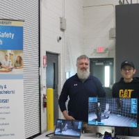 Two students standing next to an Occupational Safety & Health Management project.